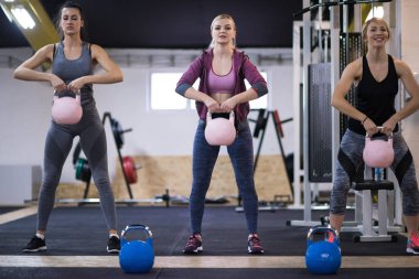 Çapraz fitness stüdyosunda kettlebell egzersizleri yapan bir grup sağlıklı genç sporcu.
