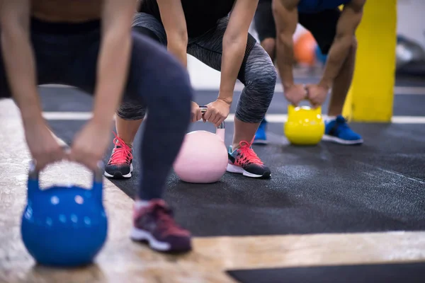 Çapraz fitness stüdyosunda kettlebell egzersizleri yapan bir grup sağlıklı genç sporcu.