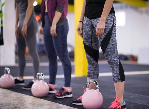 Çapraz fitness stüdyosunda kettlebell egzersizleri yapan bir grup sağlıklı genç sporcu.
