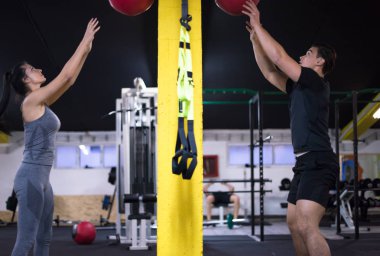 Genç sporcular spor salonunda tıbbi topla antrenman yapıyorlar.