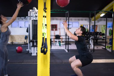 Genç sporcular spor salonunda tıbbi topla antrenman yapıyorlar.