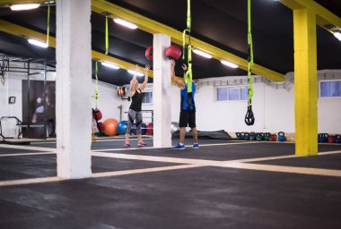 Genç sporcular spor salonunda tıbbi topla antrenman yapıyorlar.