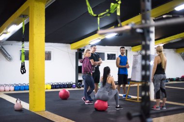 Antrenman kursu. Spor salonunda egzersiz yapmadan önce bir grup genç sporcu antrenörden talimat alıyor.