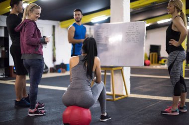 Antrenman kursu. Spor salonunda egzersiz yapmadan önce bir grup genç sporcu antrenörden talimat alıyor.