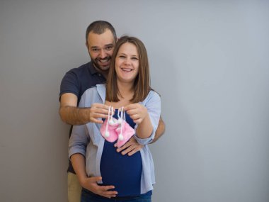 genç hamile çift yeni doğmuş bebek patiği aile ve ebeveynlik kavram beyaz arka plan üzerinde izole holding