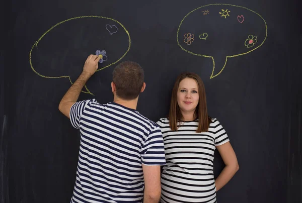 genç hamile çift onların doğmamış bebek için isim düşünmeye ve siyah bir kara tahta yazma