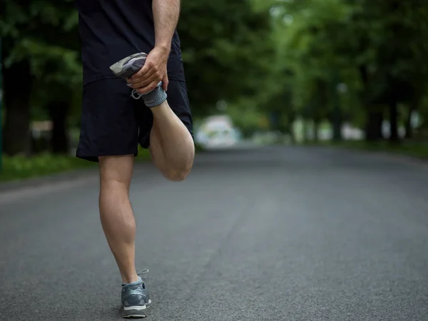 早上训练前 健康的男子跑步者在城市公园里热身和伸展身体 — 图库照片