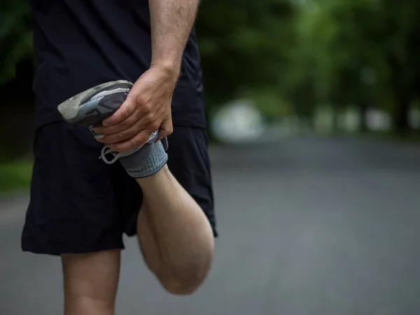 早上训练前 健康的男子跑步者在城市公园里热身和伸展身体 — 图库照片