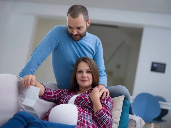 Genç hamile çift kanepede evde dinlenirken bebeğin ultrason fotoğraf arıyor