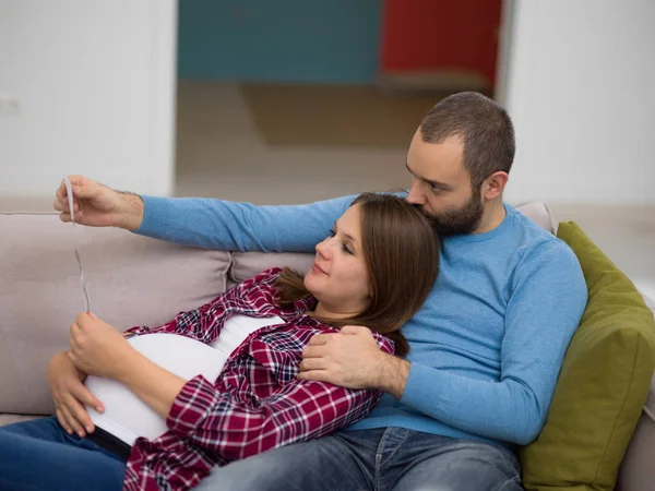 Genç hamile çift kanepede evde dinlenirken bebeğin ultrason fotoğraf arıyor