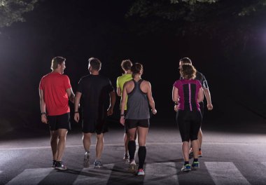 Şehir parkında koşan bir grup sağlıklı insan, gece antrenmanında koşan takım.