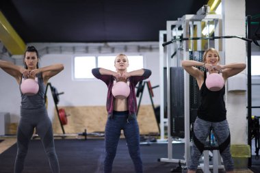 Çapraz fitness stüdyosunda kettlebell egzersizleri yapan bir grup sağlıklı genç sporcu.