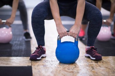 Çapraz fitness stüdyosunda kettlebell egzersizleri yapan bir grup sağlıklı genç sporcu.
