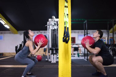Genç sporcular spor salonunda tıbbi topla antrenman yapıyorlar.