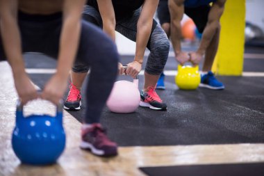 Çapraz fitness stüdyosunda kettlebell egzersizleri yapan bir grup sağlıklı genç sporcu.