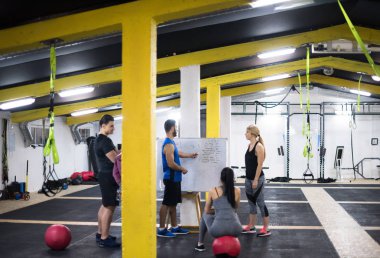 Antrenman kursu. Spor salonunda egzersiz yapmadan önce bir grup genç sporcu antrenörden talimat alıyor.