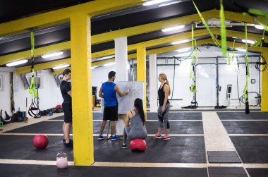 Antrenman kursu. Spor salonunda egzersiz yapmadan önce bir grup genç sporcu antrenörden talimat alıyor.