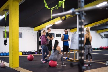 Antrenman kursu. Spor salonunda egzersiz yapmadan önce bir grup genç sporcu antrenörden talimat alıyor.