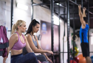 Bir grup genç kaslı sporcu, Cross fitness eğitiminin bir parçası olarak barfiks çekiyorlar.