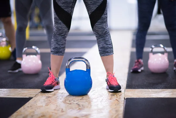 Çapraz fitness stüdyosunda kettlebell egzersizleri yapan bir grup sağlıklı genç sporcu.