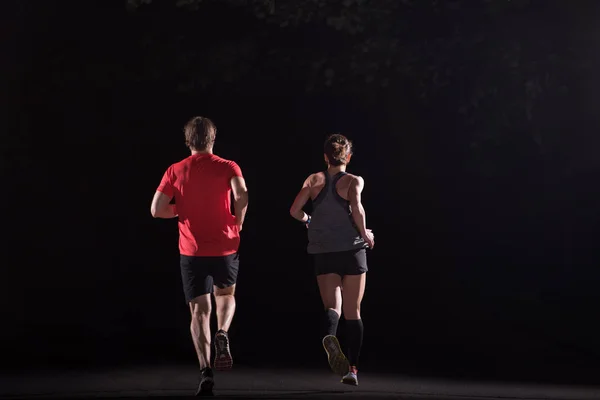 group of healthy people jogging in city park, runners team at night training