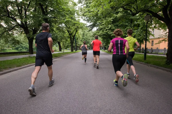 シティパークでジョギングをしている健康な人や朝のトレーニングをしているランナーのグループ — ストック写真