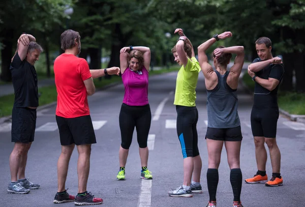 healthy runners team warming up and stretching in city park before morning training