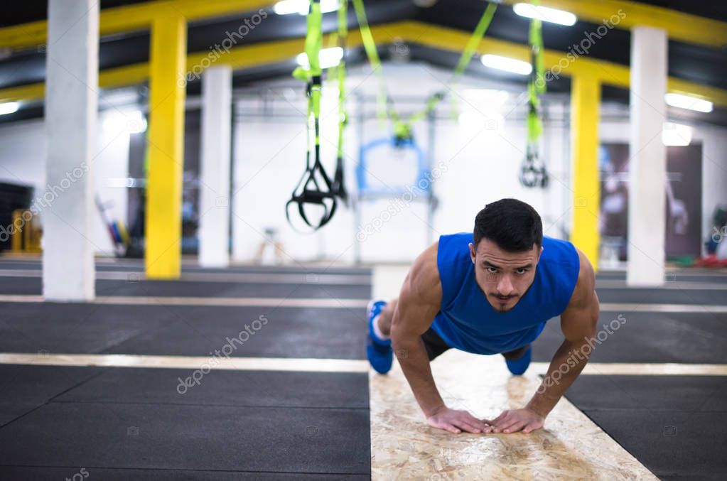 Young strong man doing pushups  at cross fitness gym