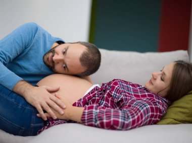 Mutlu gelecek babam kanepeye evde dinlenirken onun hamile eşi göbek dinleme