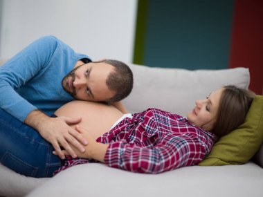 Mutlu gelecek babam kanepeye evde dinlenirken onun hamile eşi göbek dinleme