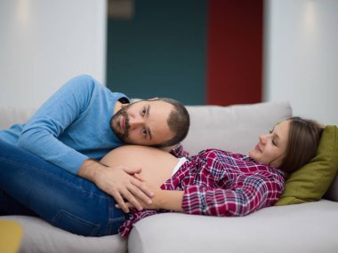 Mutlu gelecek babam kanepeye evde dinlenirken onun hamile eşi göbek dinleme