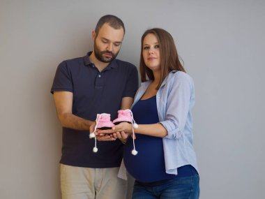 genç hamile çift yeni doğmuş bebek patiği aile ve ebeveynlik kavram beyaz arka plan üzerinde izole holding