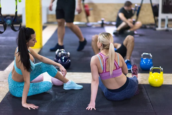 bir grup genç sporcuların katta oturan ve çapraz fitness spor egzersiz sonrası rahatlatıcı