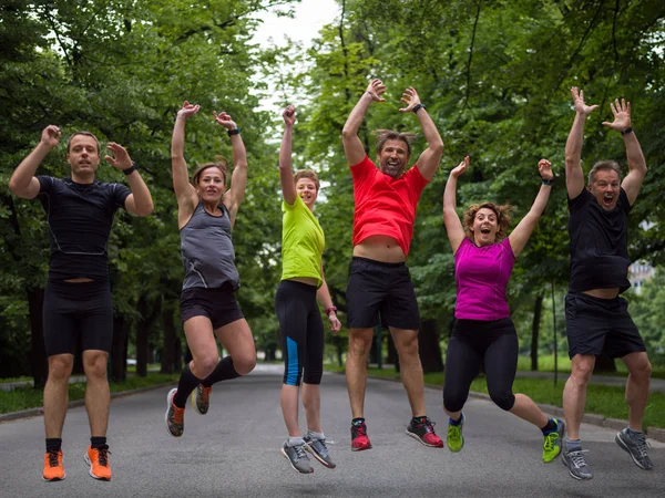 group of healthy runners team jumping in the air at city park during  morning training