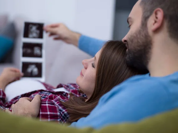 Mladí Těhotná Pár Hledá Ultrazvuk Foto Dítěte Při Odpočinku Pohovce — Stock fotografie