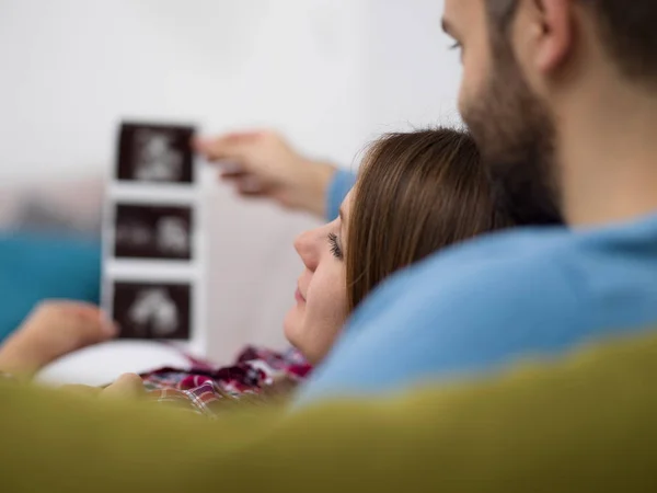 Mladí Těhotná Pár Hledá Ultrazvuk Foto Dítěte Při Odpočinku Pohovce — Stock fotografie