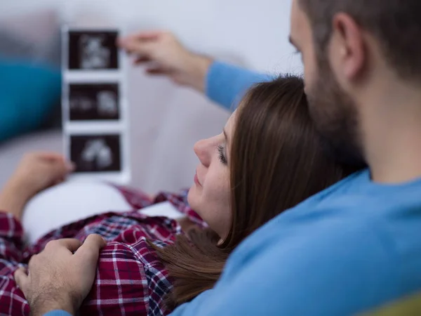 Mladí Těhotná Pár Hledá Ultrazvuk Foto Dítěte Při Odpočinku Pohovce — Stock fotografie