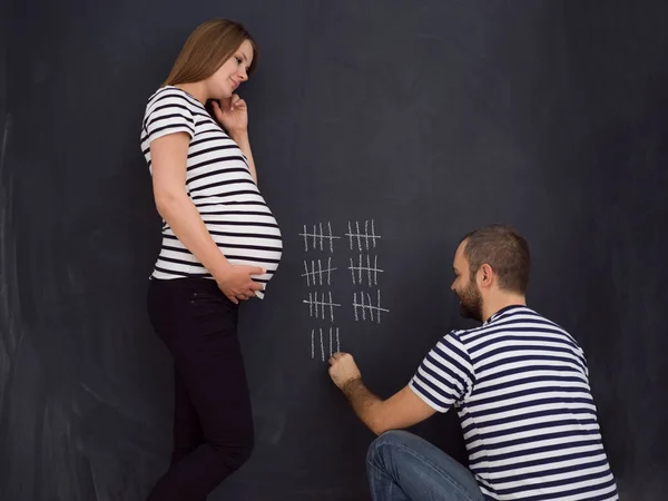 年轻怀孕夫妇帐户的怀孕周和写在黑板上粉笔 — 图库照片