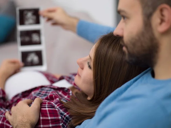 Mladí Těhotná Pár Hledá Ultrazvuk Foto Dítěte Při Odpočinku Pohovce — Stock fotografie