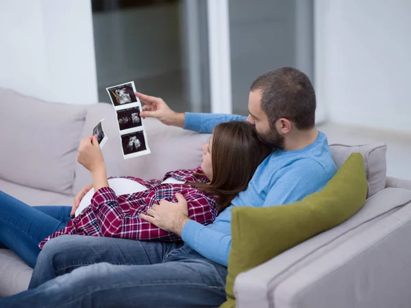 Mladí Těhotná Pár Hledá Ultrazvuk Foto Dítěte Při Odpočinku Pohovce — Stock fotografie