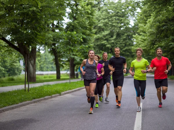 シティパークでジョギングをしている健康な人や朝のトレーニングをしているランナーのグループ — ストック写真