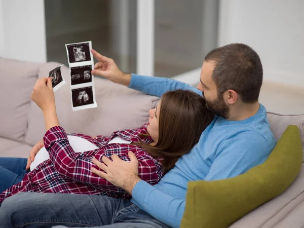 Mladí Těhotná Pár Hledá Ultrazvuk Foto Dítěte Při Odpočinku Pohovce — Stock fotografie