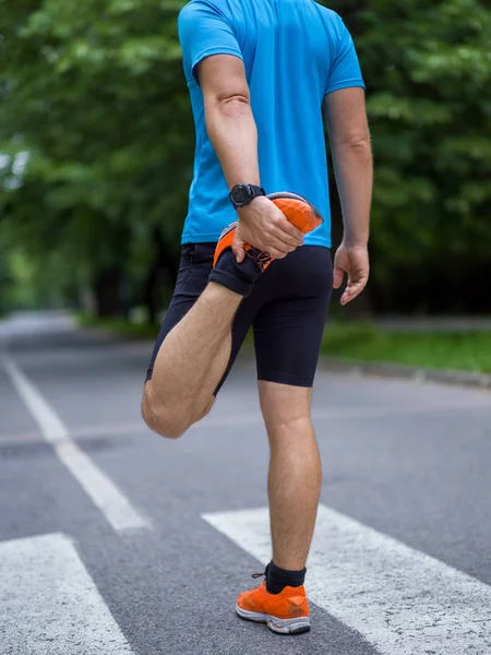 健康な男性ランナーが朝のトレーニングの前に街の公園で温暖化やストレッチ — ストック写真