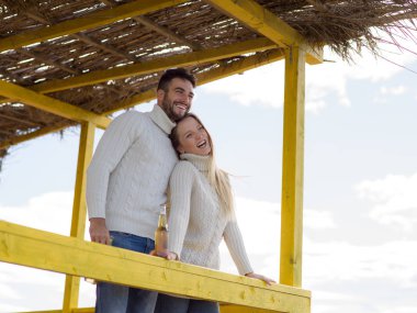 Sonbahar boyunca boş sahil barında birlikte bira içen çift.