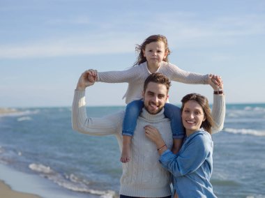 Küçük kızıyla bir aile sonbahar günü kumsalda dinleniyor ve eğleniyor.