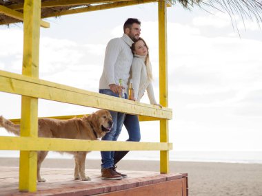 Sonbahar boyunca boş sahil barında birlikte bira içen çift.