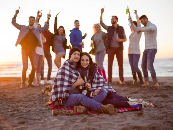 Pareja Joven Sentada Con Amigos Alrededor Campfire Beach Atardecer Bebiendo —  Fotos de Stock