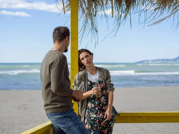 Sonbahar boyunca boş sahil barında birlikte bira içen çift.