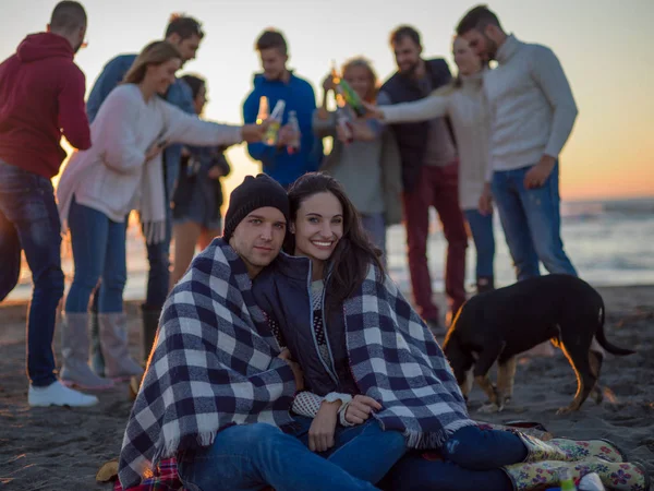 Pareja Joven Sentada Con Amigos Alrededor Campfire Beach Atardecer Bebiendo —  Fotos de Stock