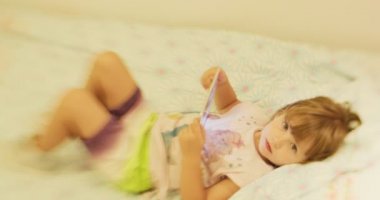 Küçük kız evde tabletle oynuyor. 